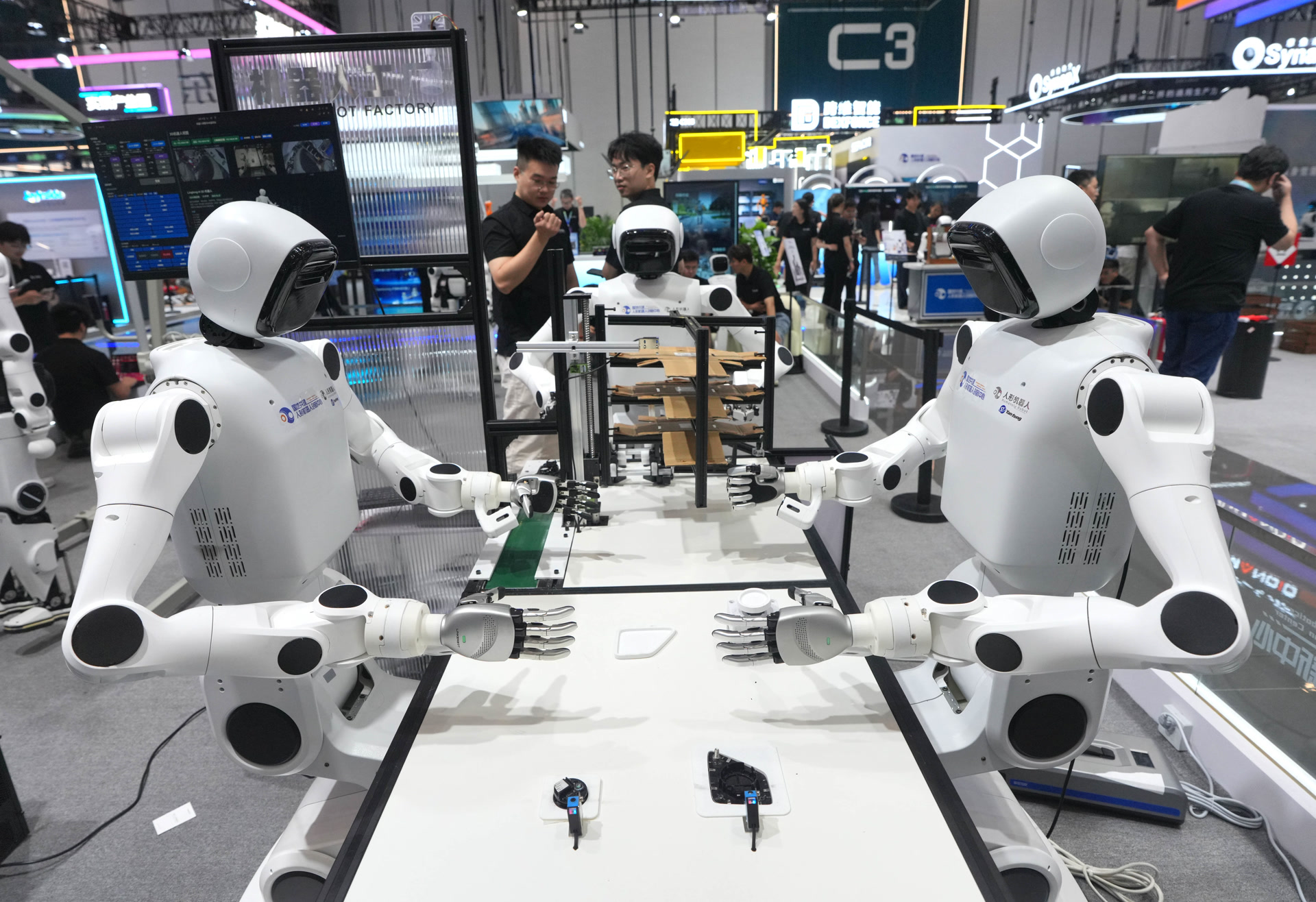 2026世界机器人大会：国地共建具身智能机器人创新中心展位上，多台人形机器人在操作台协同作业。
